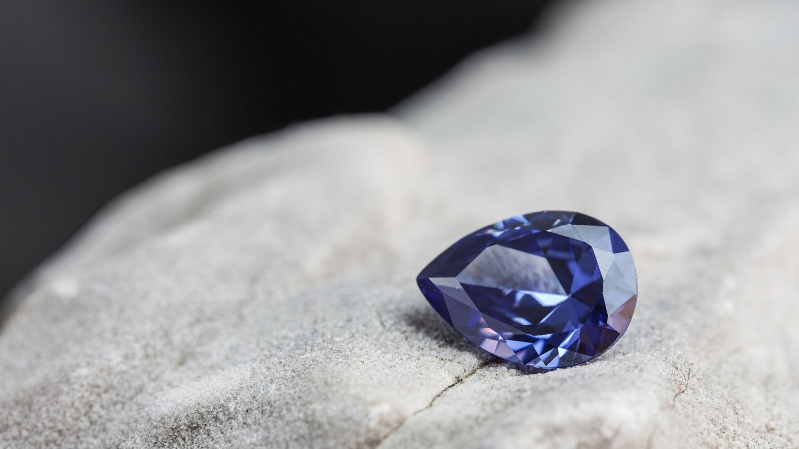 A glimmering natural purple sapphire gemstone on a rock surface